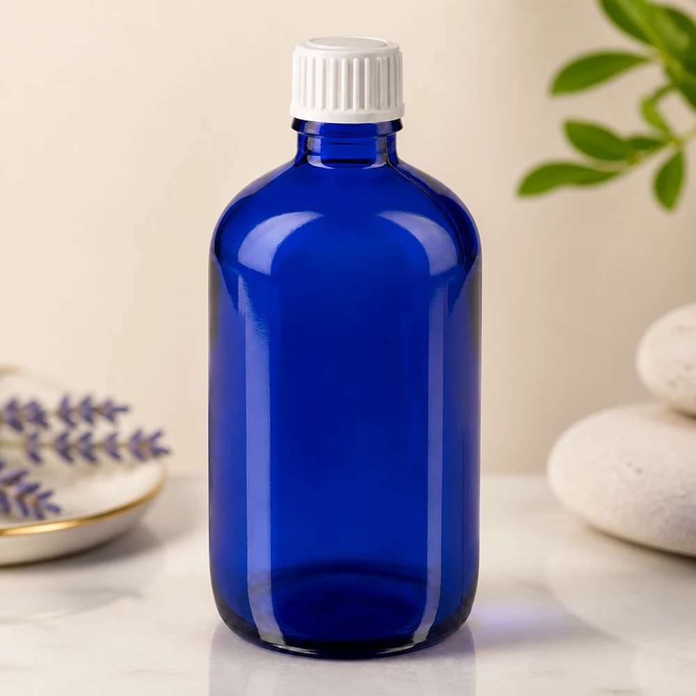 Frasco de vidro azul de 100 ml com tampa de segurança para crianças branca, sobre uma superfície de mármore, ao lado de lavanda