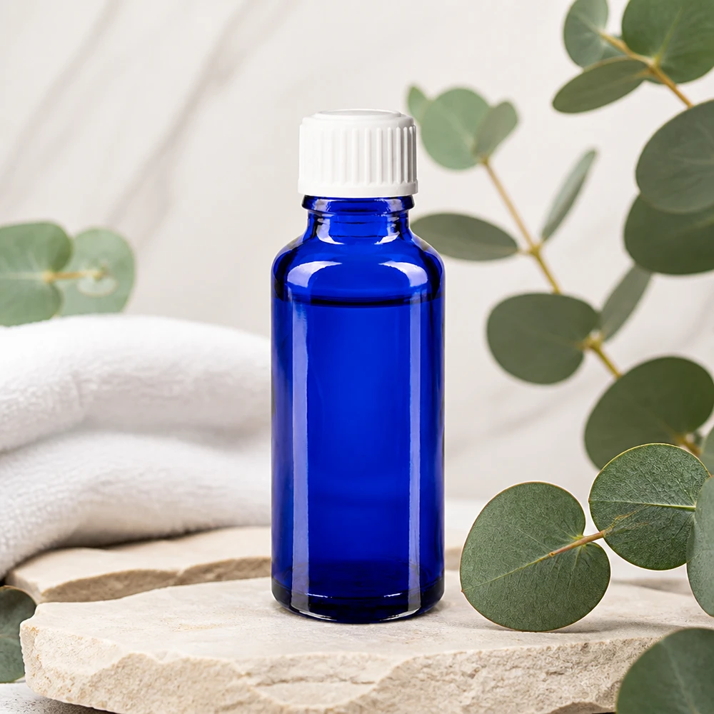 Frasco de farmácia azul cobalto de 30 ml com tampa conta-gotas branca sobre pedra natural com aroma a eucalipto