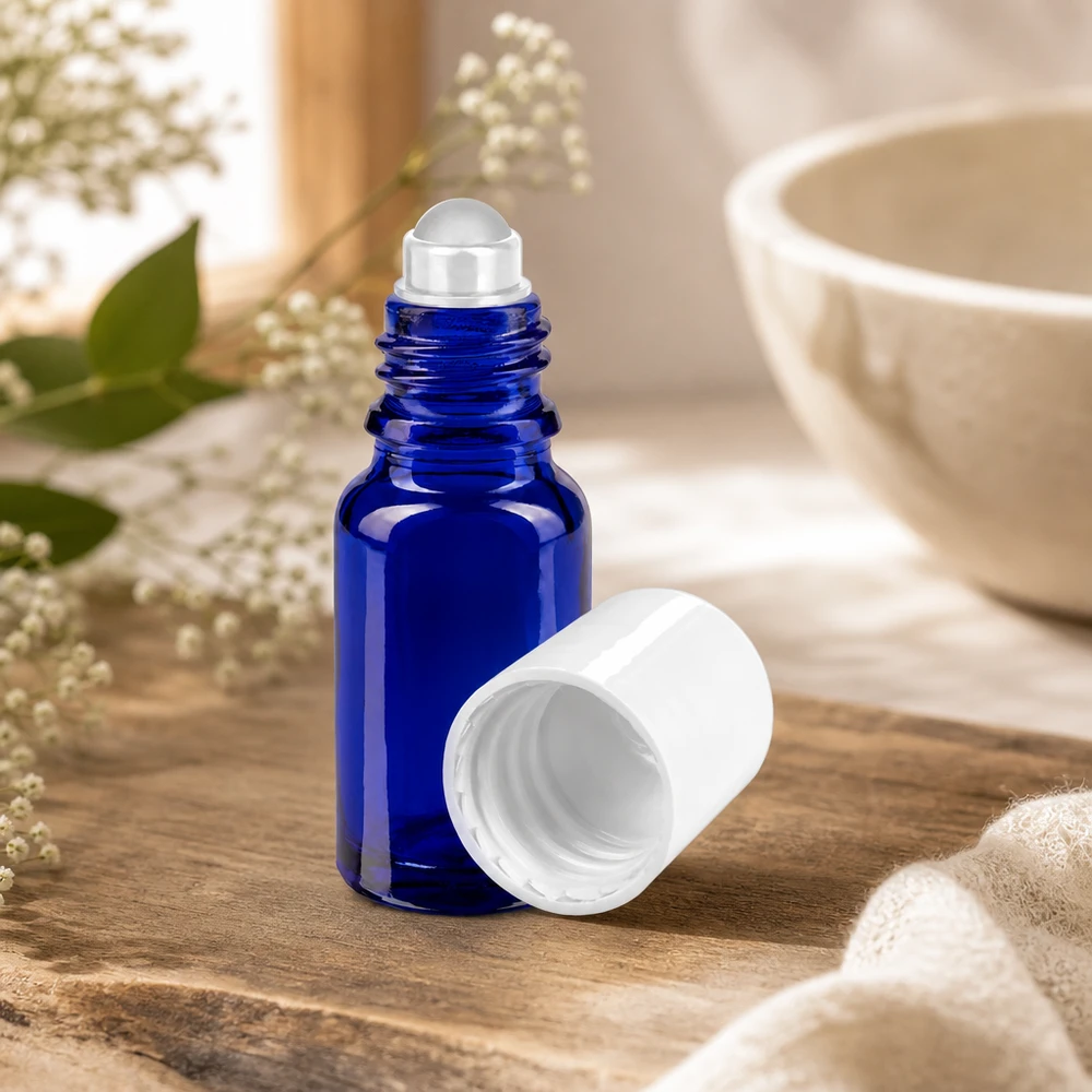 Frasco de farmácia azul 10ml tampa roll-on branca Frasco de vidro azul cobalto de 10 ml com aplicador roll-on, aberto e sem a tampa branca, sobre um fundo de madeira