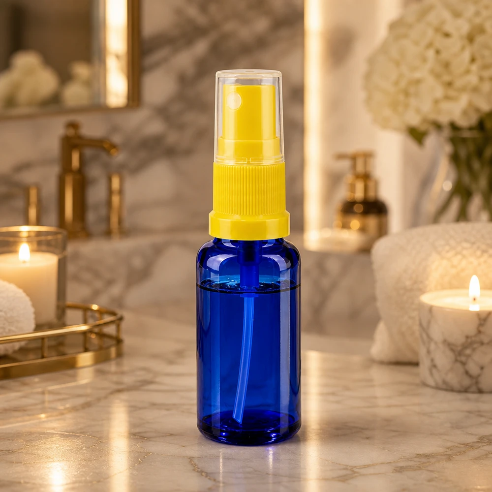 Frasco de farmácia azul 20ml spray top amarelo Frasco pulverizador de vidro azul de 20 ml com bico pulverizador amarelo sobre uma prateleira de casa de banho em mármore