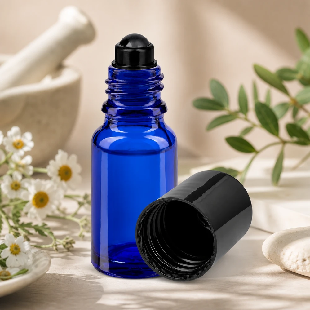 Frasco de farmácia azul 10ml tampa roll-on preta Frasco roll-on azul de 10 ml STD com tampa preta, ao lado de ervas de almofariz e flores de camomila