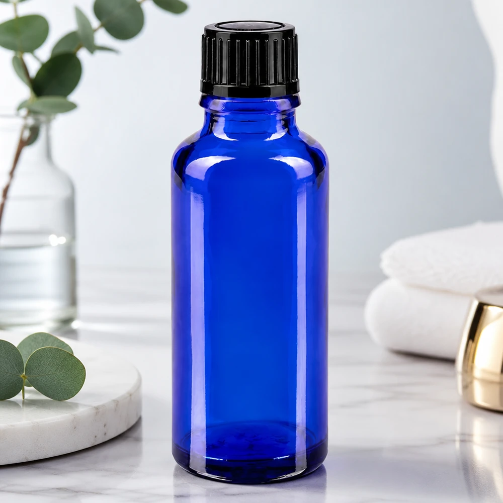 Frasco de vidro azul cobalto de 30 ml com tampa de rosca preta sobre uma superfície de mármore branco