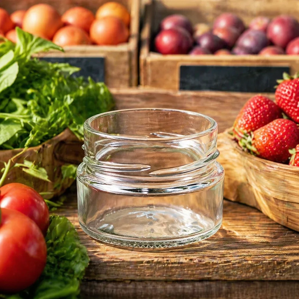 Frasco redondo de 80ml sem tampa (TO58deep) UNiTWIST UNiTWIST Runda80 frasco redondo de 80 ml TO58deep frasco de conserva vazio em cima de uma mesa de madeira com frutas e legumes frescos ao fundo