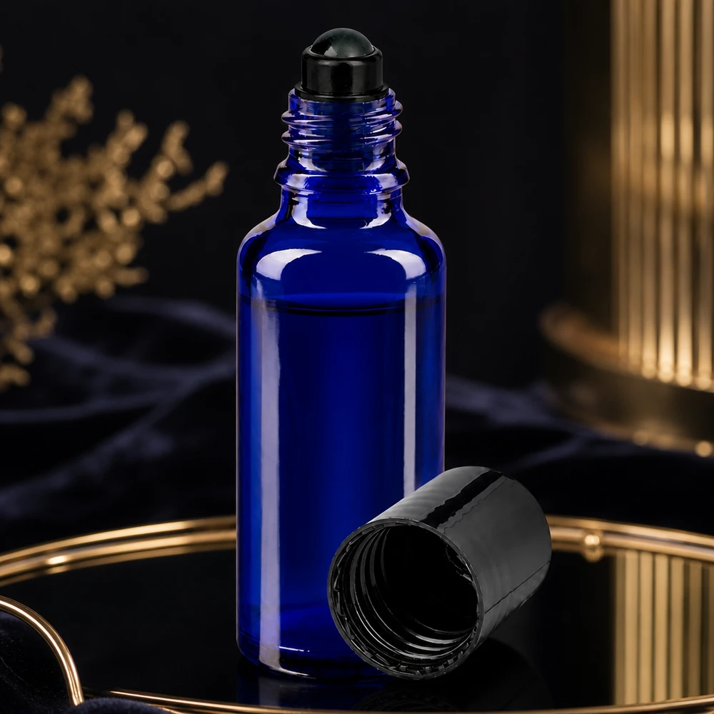 Frasco de farmácia azul 30ml com tampa de rosca preta Frasco azul de 30 ml com aplicador roll-on, com a tampa de rosca preta aberta, numa bandeja dourada