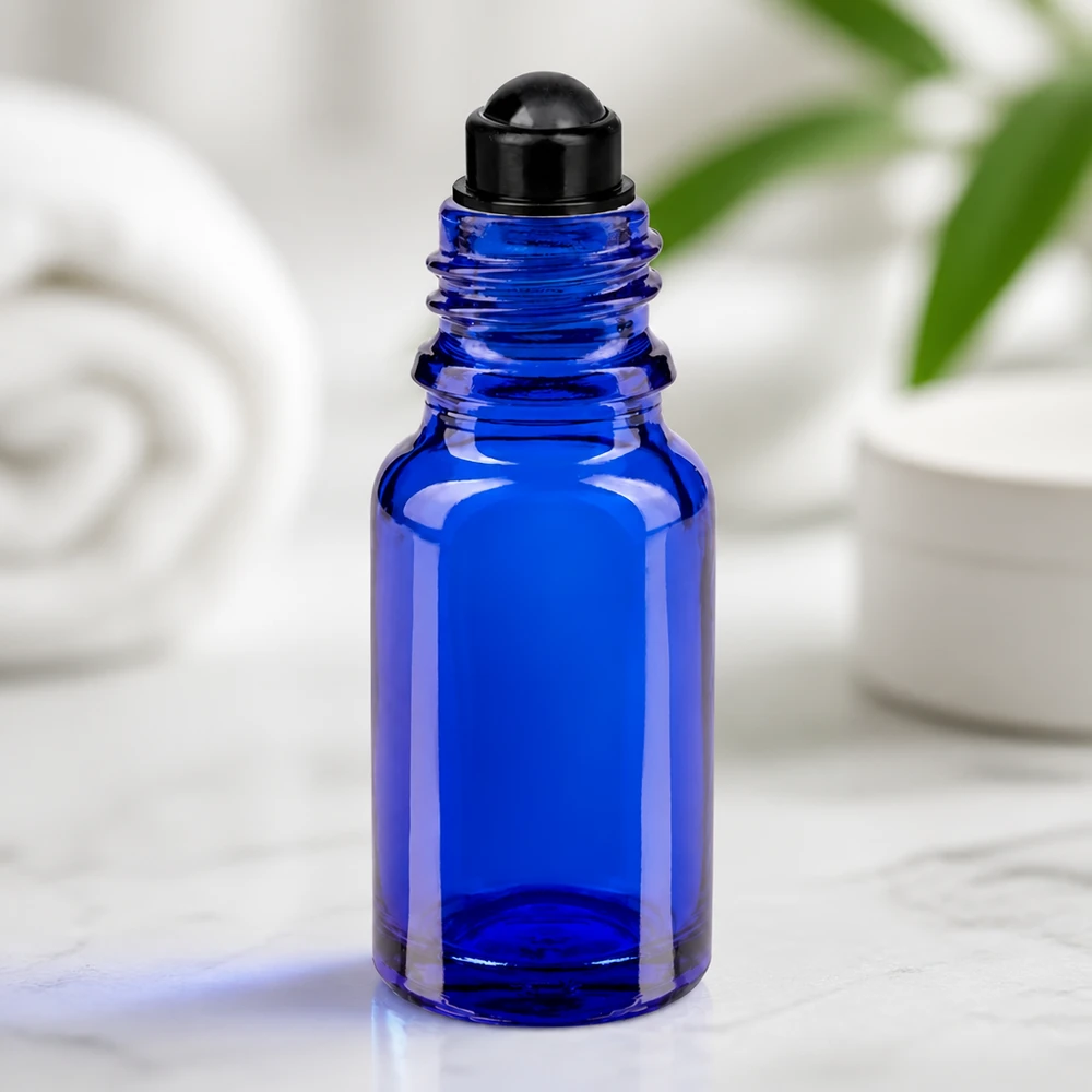 Frasco de vidro azul de 10 ml com aplicador roll-on preto sobre mármore, num fundo branco