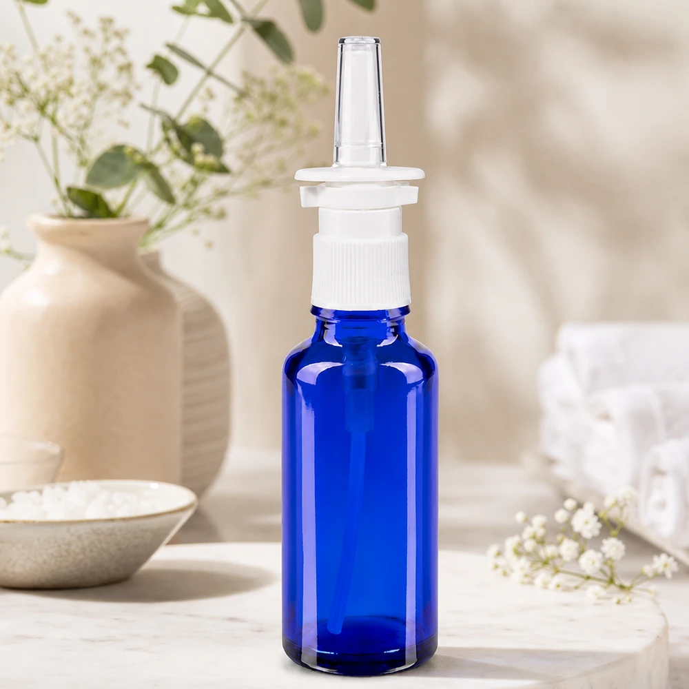 Imagem em grande plano de um frasco de spray nasal de 30 ml, azul cobalto, com cabeça de bomba de rosca branca e bico de plástico transparente
