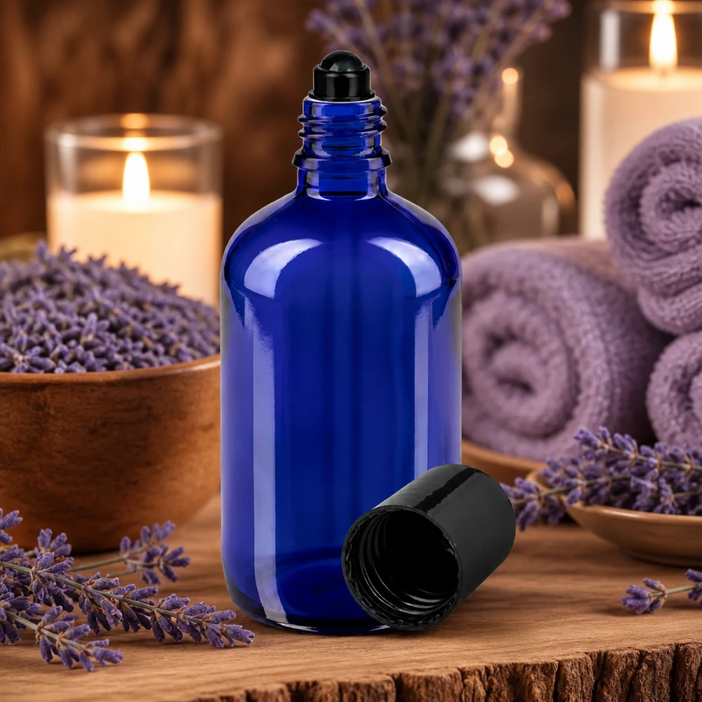 Frasco de farmácia azul 100ml tampa roll-on preta Frasco de vidro azul de 100 ml com tampa roll-on, rodeado por flores de lavanda e velas