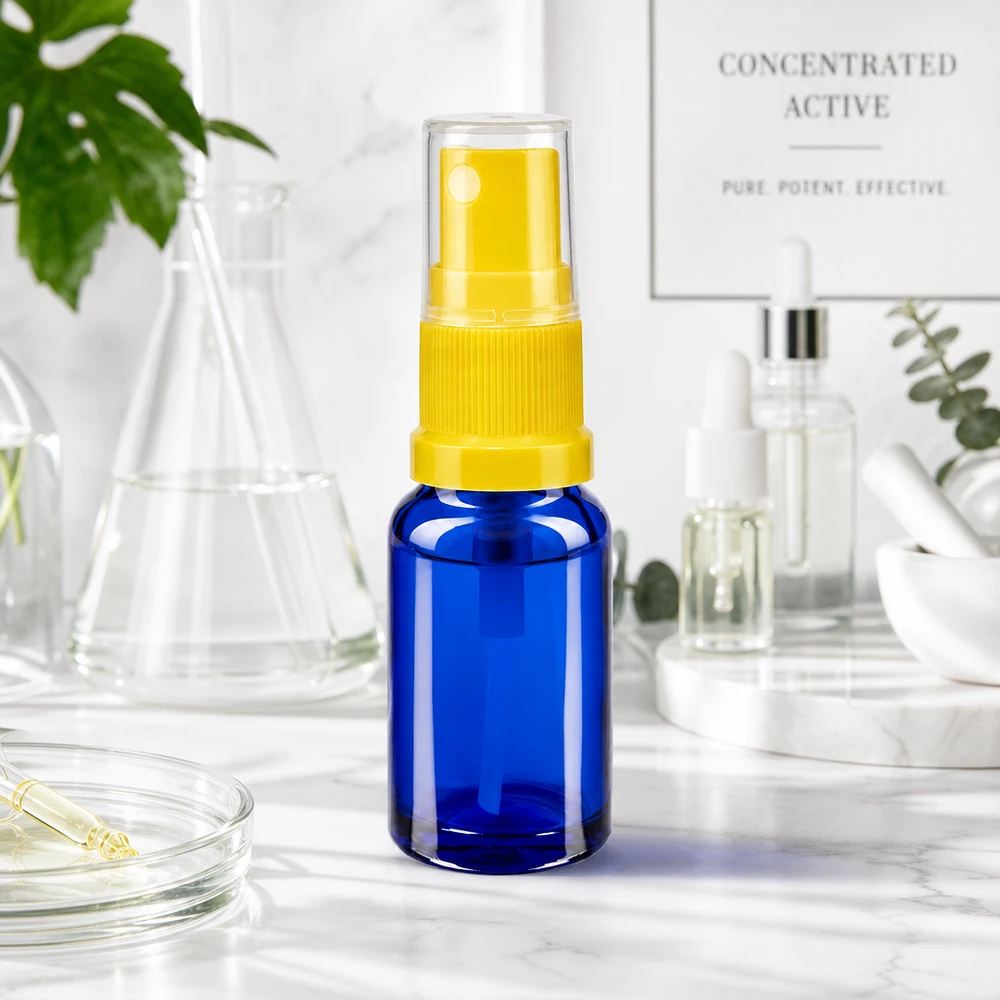Frasco de farmácia azul 10ml spray top amarelo Frasco azul de 10 ml com mecanismo de pulverização amarelo e tampa de proteção sobre uma superfície de mármore branco