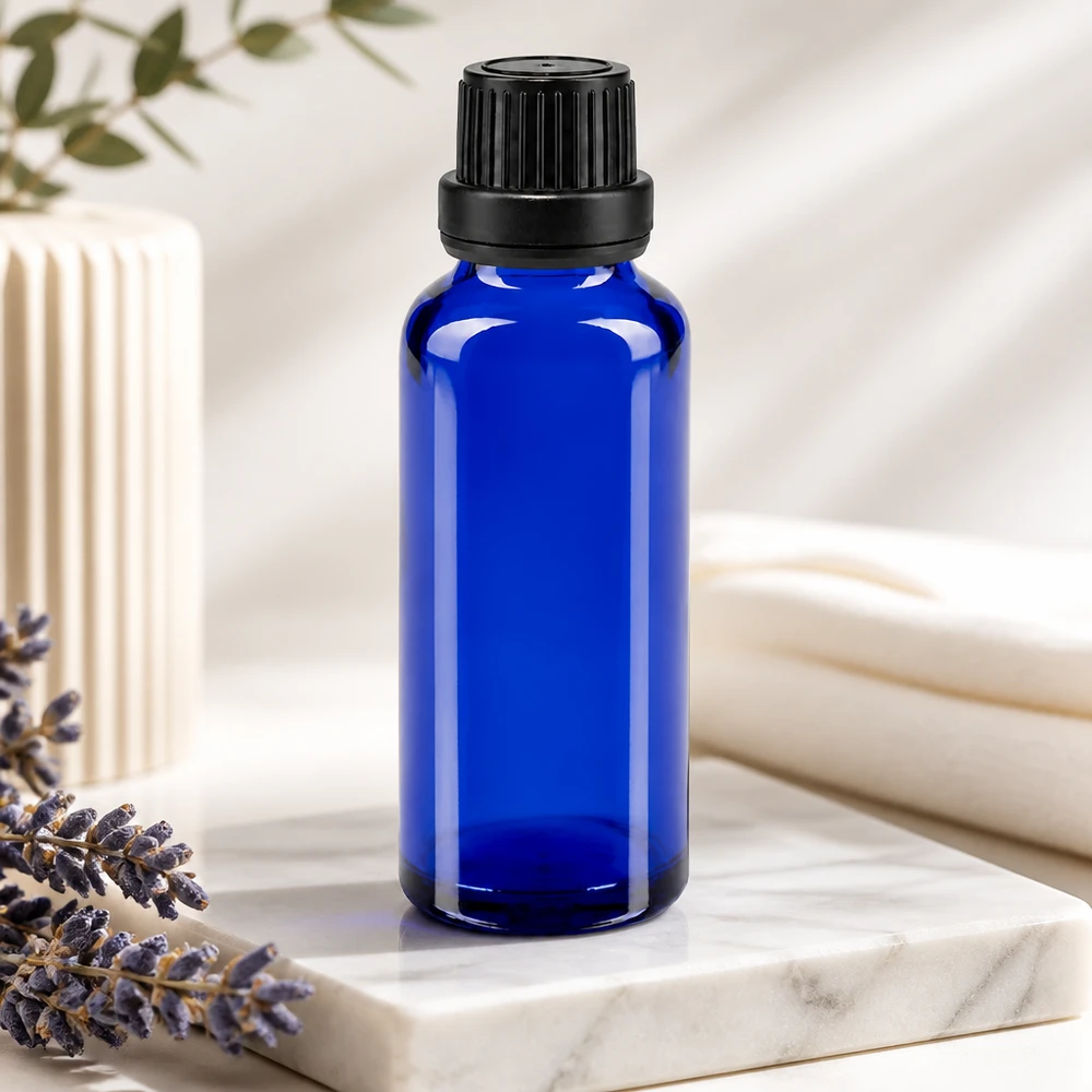 Frasco conta-gotas ApoGlas azul de 30 ml com inserção de 2 mm e tampa preta ao lado de lavanda sobre mármore