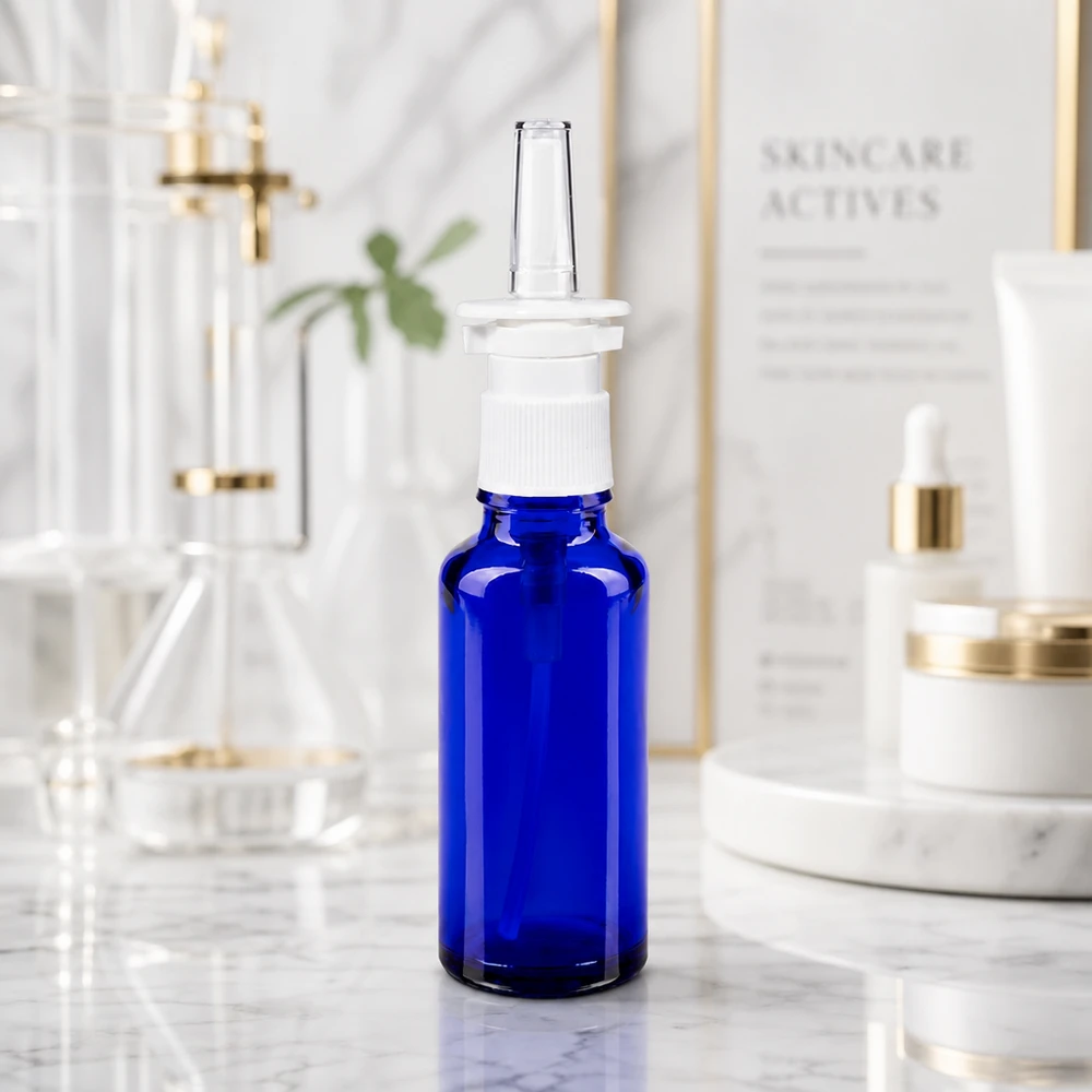 Frasco de vidro azul cobalto de 30 ml com bico pulverizador branco sobre fundo de mármore