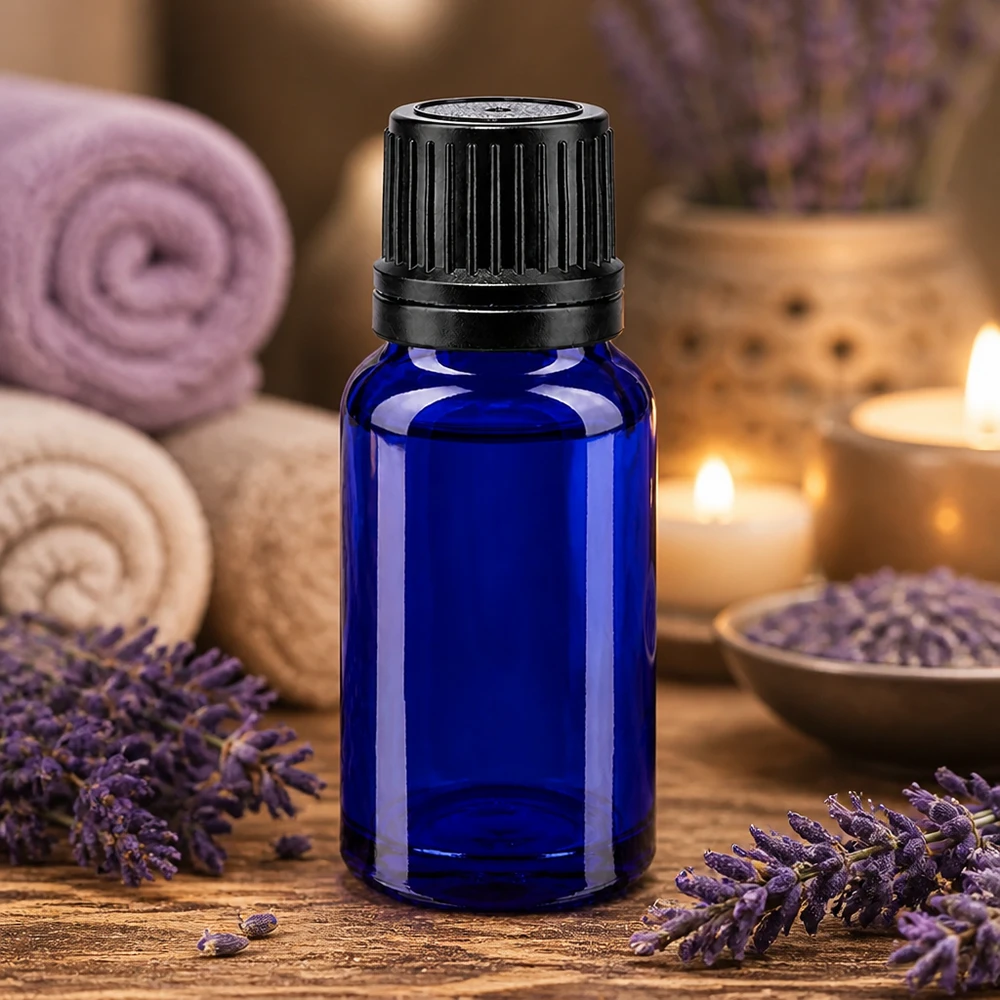 Pequeno frasco de vidro azul de 10 ml com a tampa preta original, rodeado por flores de lavanda e velas