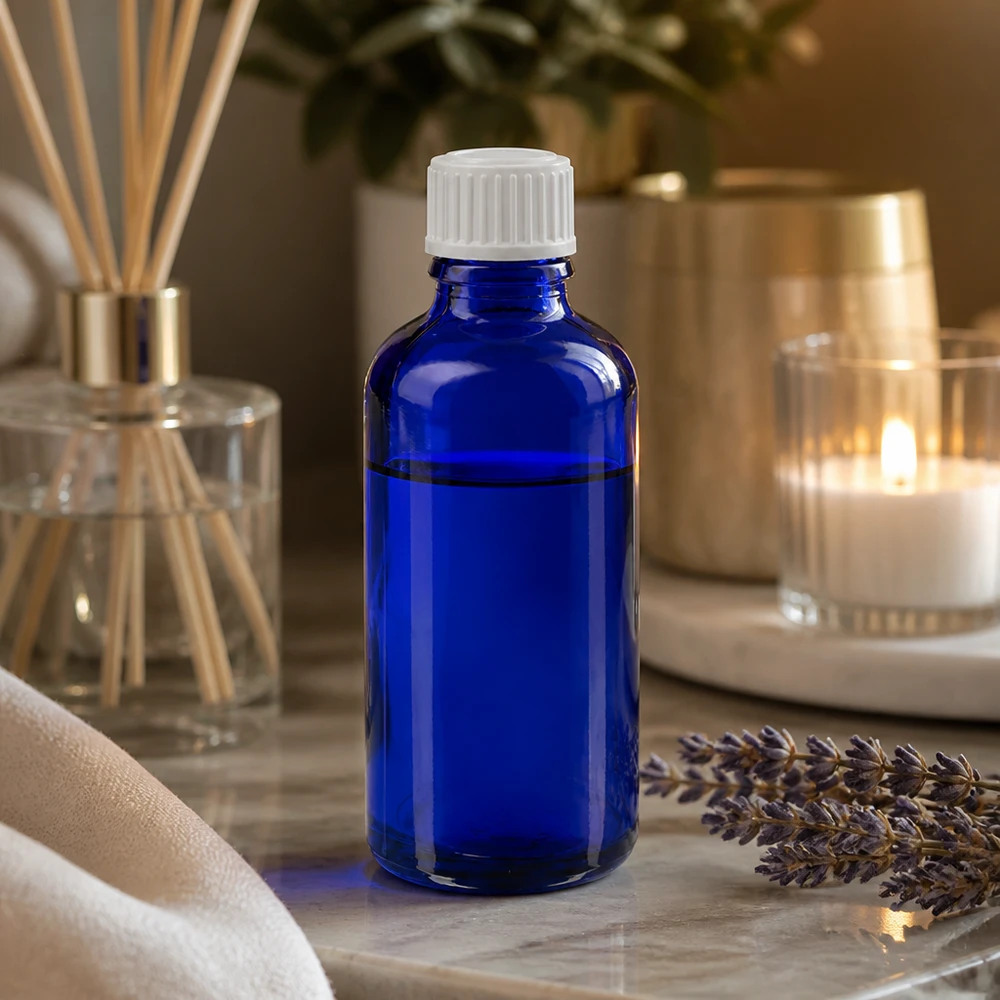 Frasco de farmácia azul 50ml tampa conta-gotas branco 0.8mm standard Frasco de vidro azul de 50 ml com tampa conta-gotas, em cima de uma superfície de mármore, ao lado de lavanda e de um difusor de aroma para o ambiente