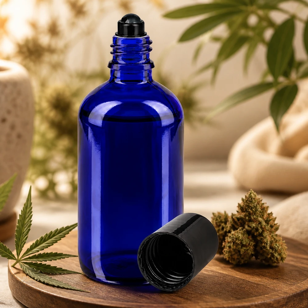 Frasco azul de 100 ml com aplicador de rolo, em vidro de farmácia, ao lado de uma flor de canábis e de uma folha de cânhamo sobre uma tábua de madeira