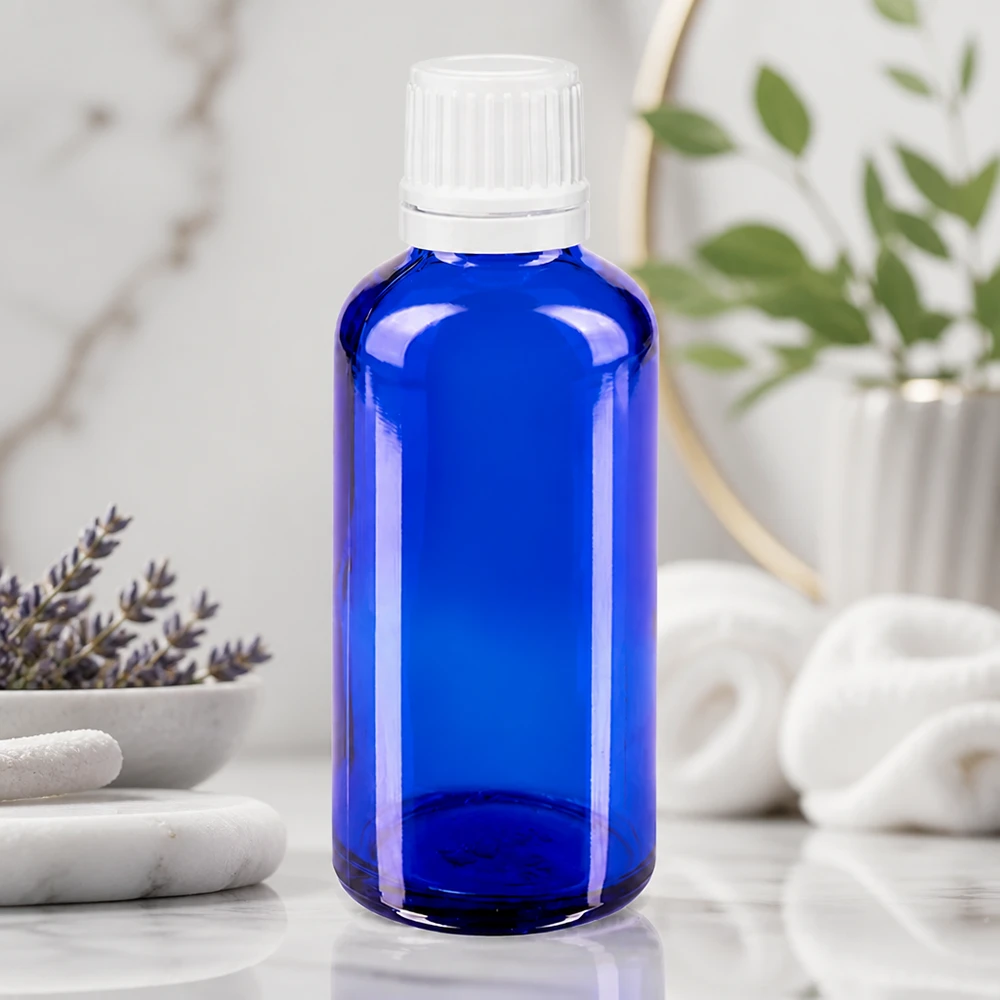 Frasco de farmácia azul 50ml tampa conta-gotas 1.2mm branco fecho inviolável Garrafa de vidro azul de 50 ml com tampa de rosca branca sobre mármore, ao lado de lavanda