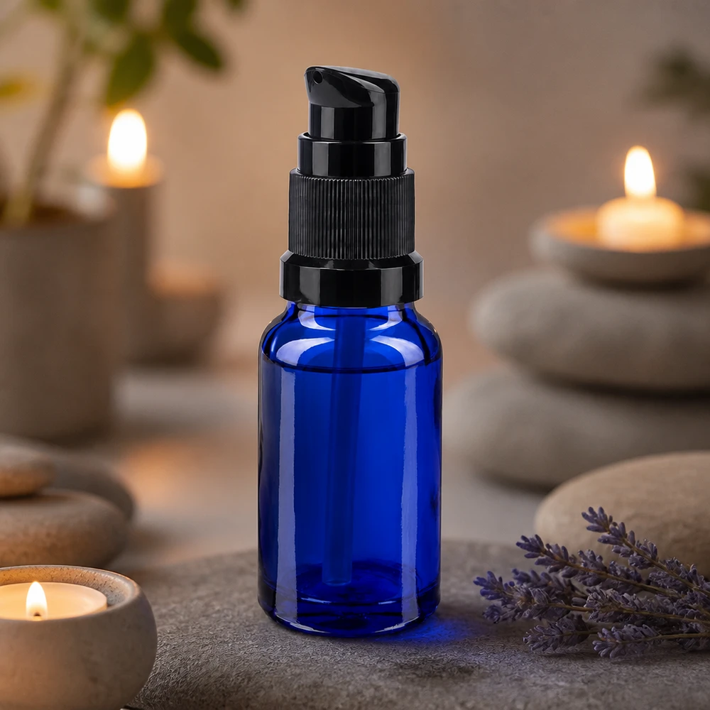 Frasco de vidro de farmácia azul de 10 ml com tampa de bomba preta, ao lado de lavanda e velas