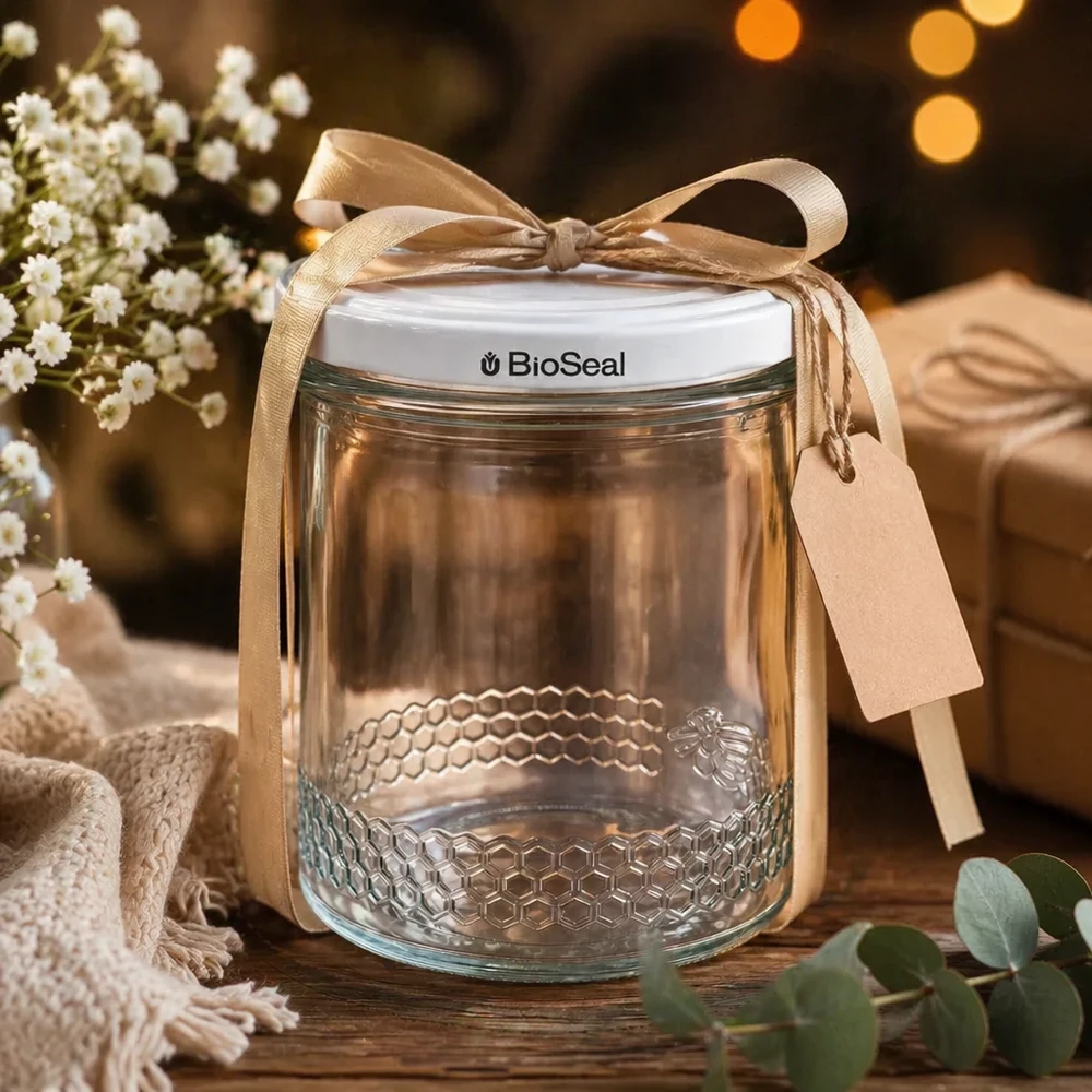 Frasco de mel de 400 ml vazio com tampa BioSeal branca para oferta, decorado com um laço dourado e um pendente