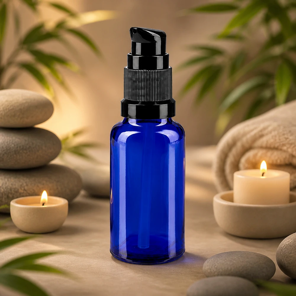 Frasco azul de 20 ml com bomba, em vidro de farmácia, com cabeça de bomba preta, ao lado de pedras de massagem e velas