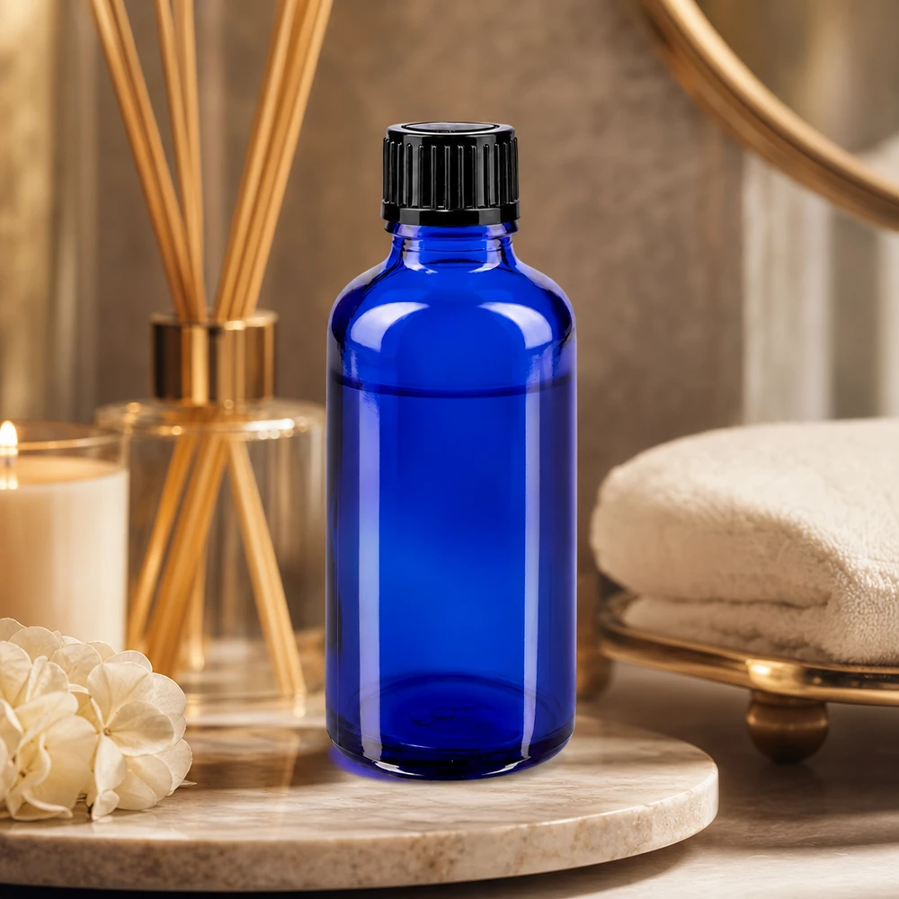 Frasco conta-gotas de 50 ml em vidro de farmácia, de cor azul cobalto, com tampa de rosca preta, num ambiente de spa