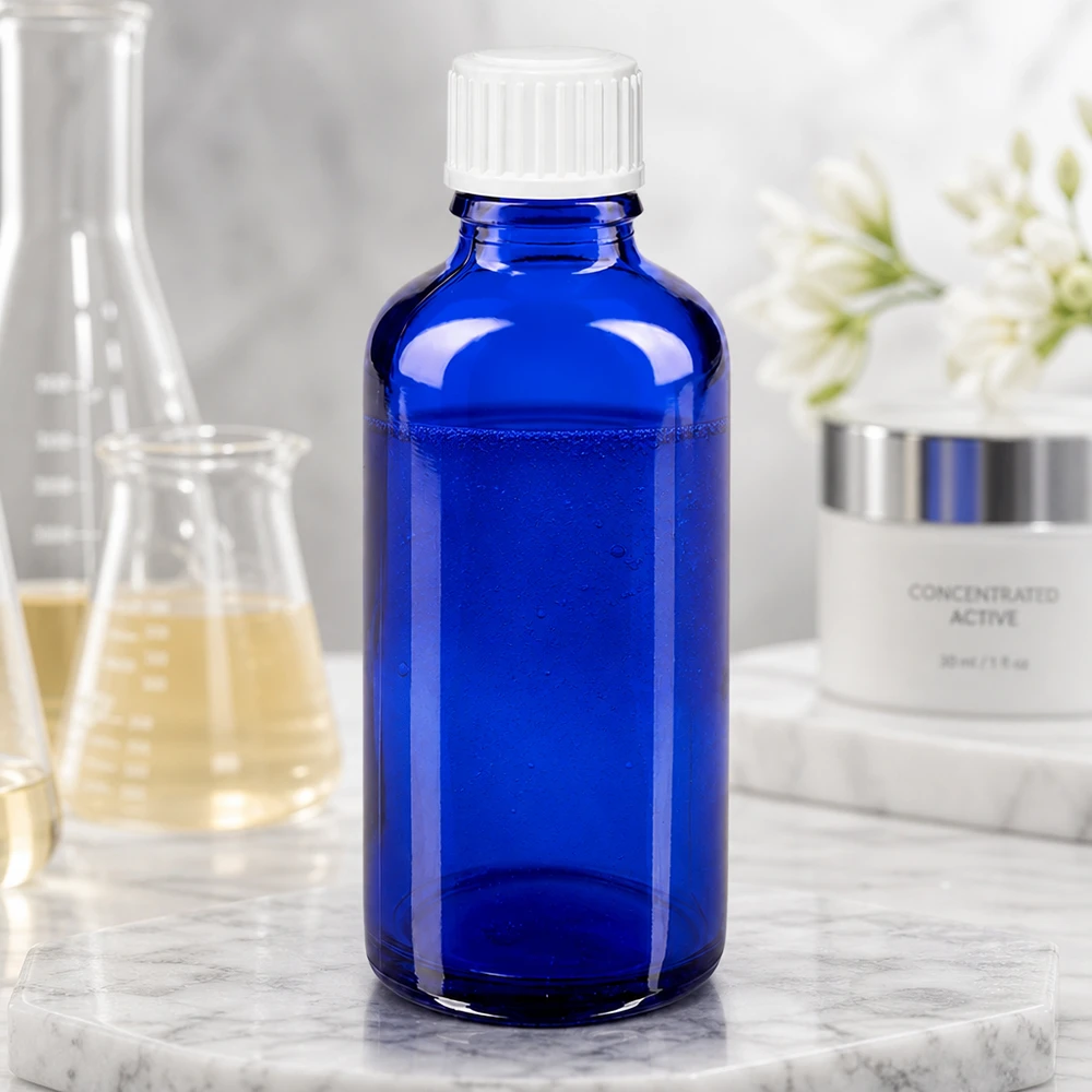 Frasco de farmácia azul 50ml tampa de rosca branco standard Frasco de vidro azul cobalto de 50 ml com tampa de rosca branca, ao lado de um balão de laboratório e de um creme para a pele