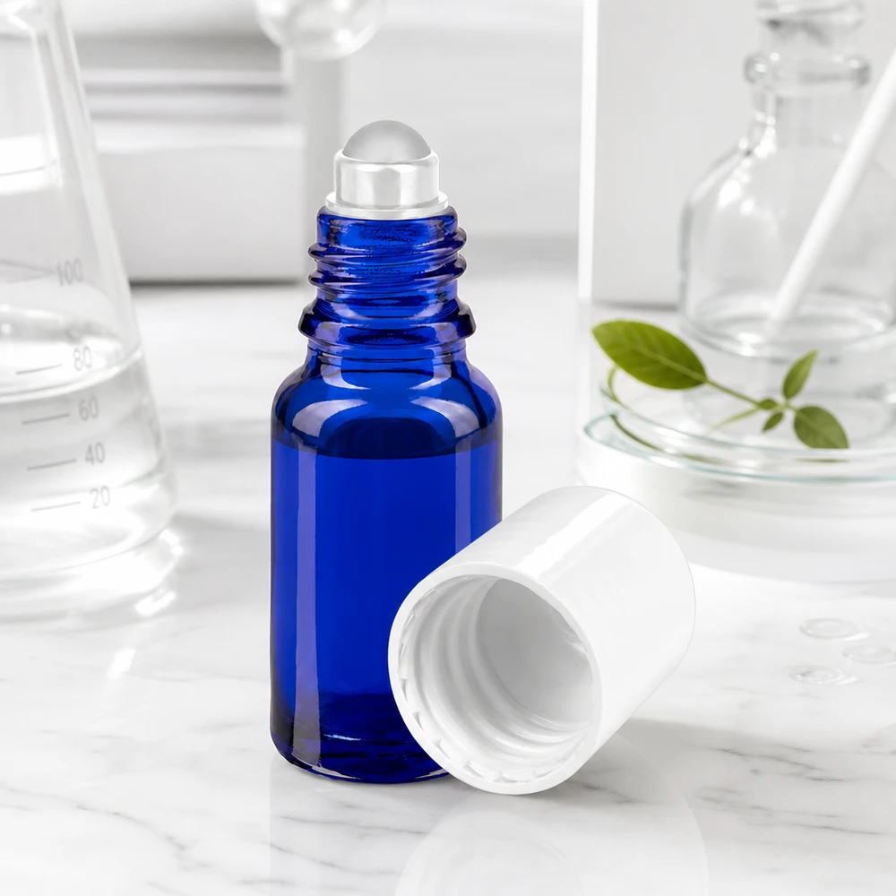 Frasco roll-on azul cobalto de 10 ml com esfera de vidro transparente e tampa branca sobre fundo de mármore