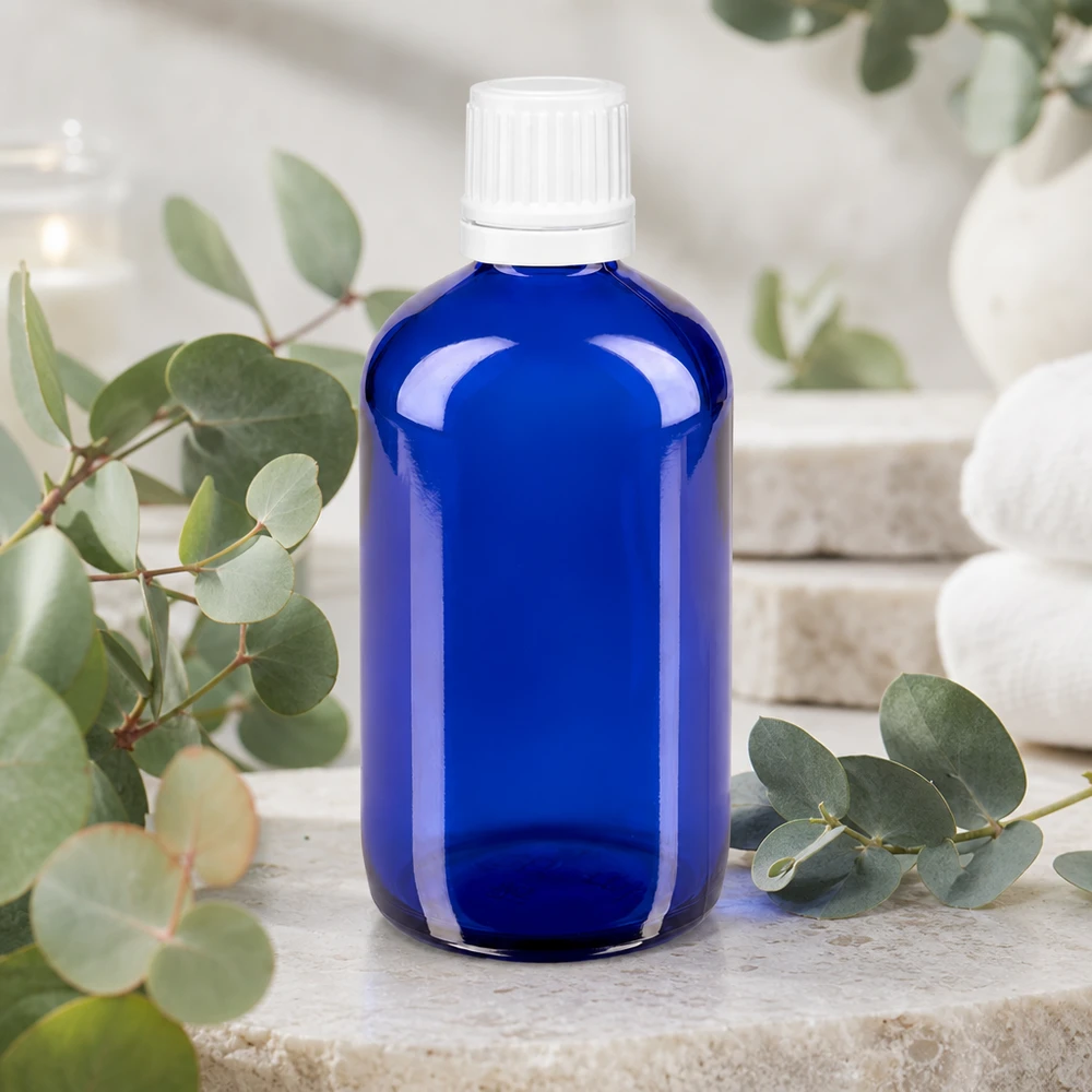 Frasco de farmácia azul 100ml tampa de rosca branca fecho inviolável Frasco de farmácia azul cobalto de 100 ml com tampa de segurança branca, sobre pedra natural com ramos de eucalipto