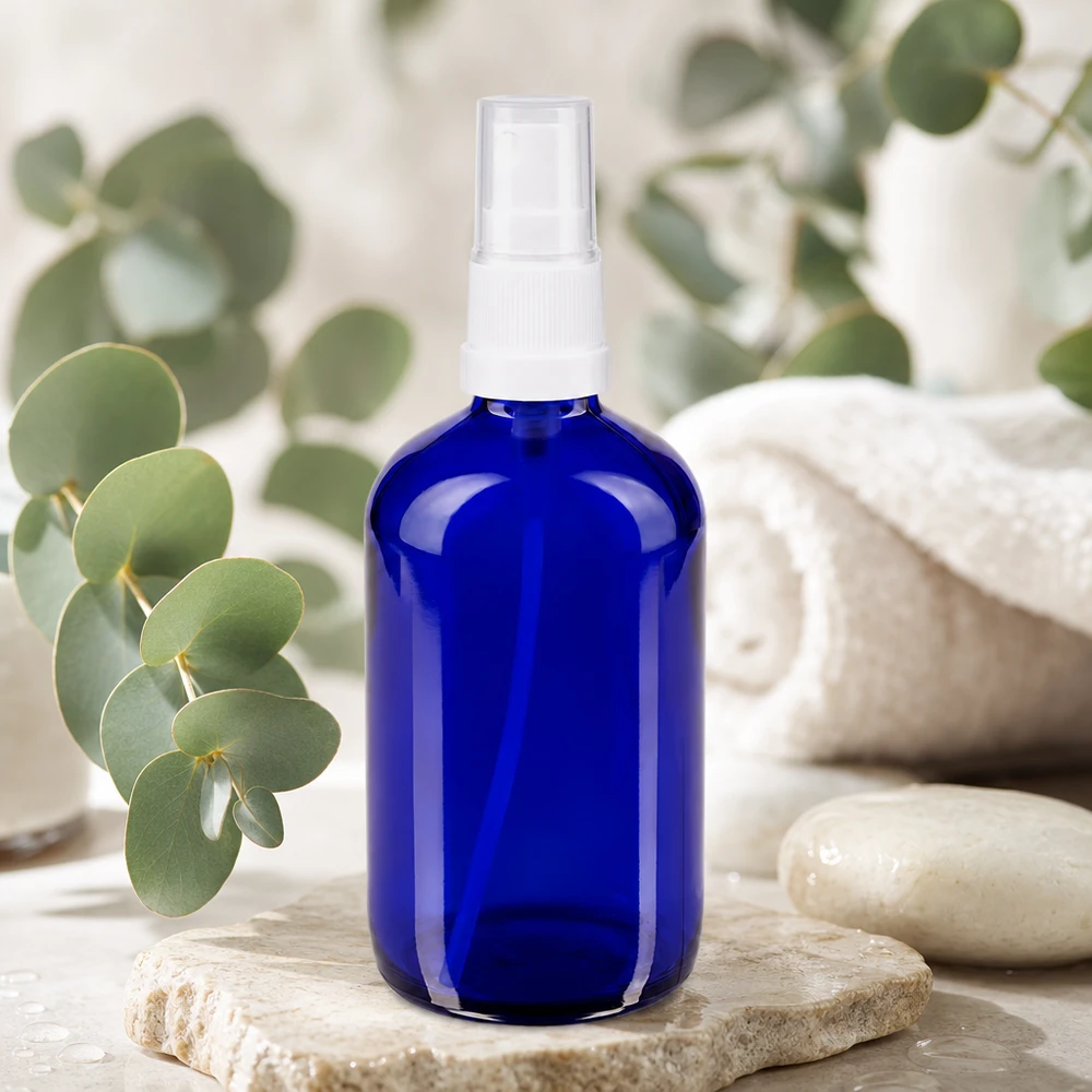 Frasco de farmácia azul 100ml spray anexo branco Frasco de spray redondo de 100 ml em vidro azul com proteção UV, com pulverizador branco sobre pedra natural