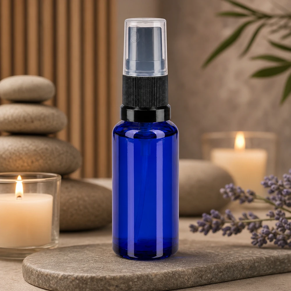 Pequeno frasco pulverizador de 30 ml em vidro de farmácia azul cobalto com bico pulverizador preto sobre fundo de pedra