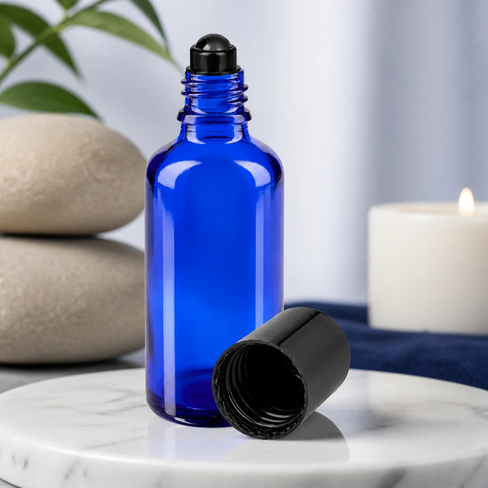 Frasco de vidro azul de 50 ml com aplicador roll-on preto e tampa removida sobre mármore