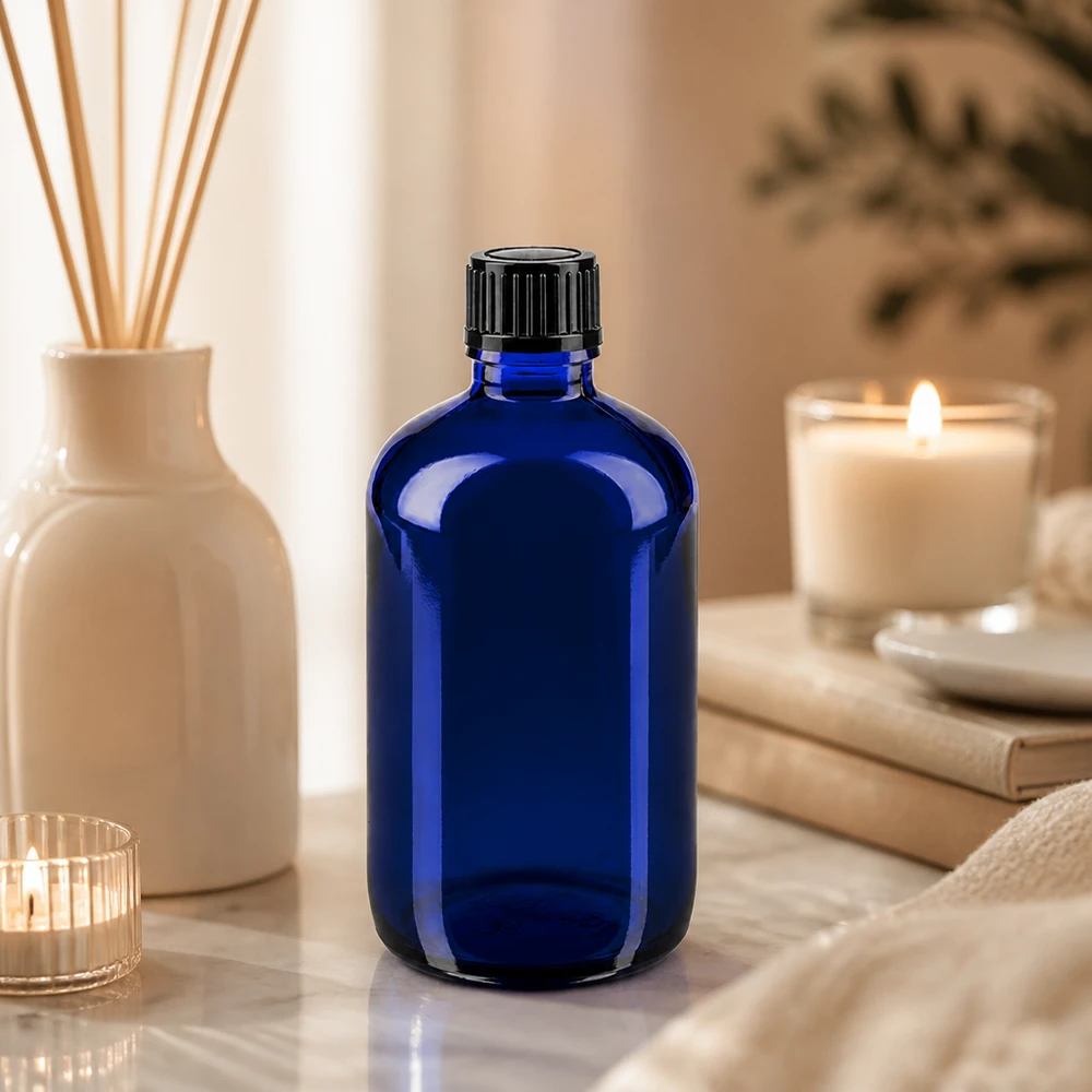 Frasco de farmácia azul cobalto de 100 ml com tampa conta-gotas preta sobre fundo de mármore