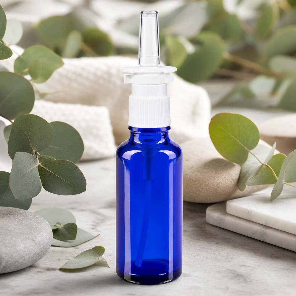 Frasco de spray nasal de 30 ml, azul cobalto, com bico de pressão branco e ramos de eucalipto como decoração natural