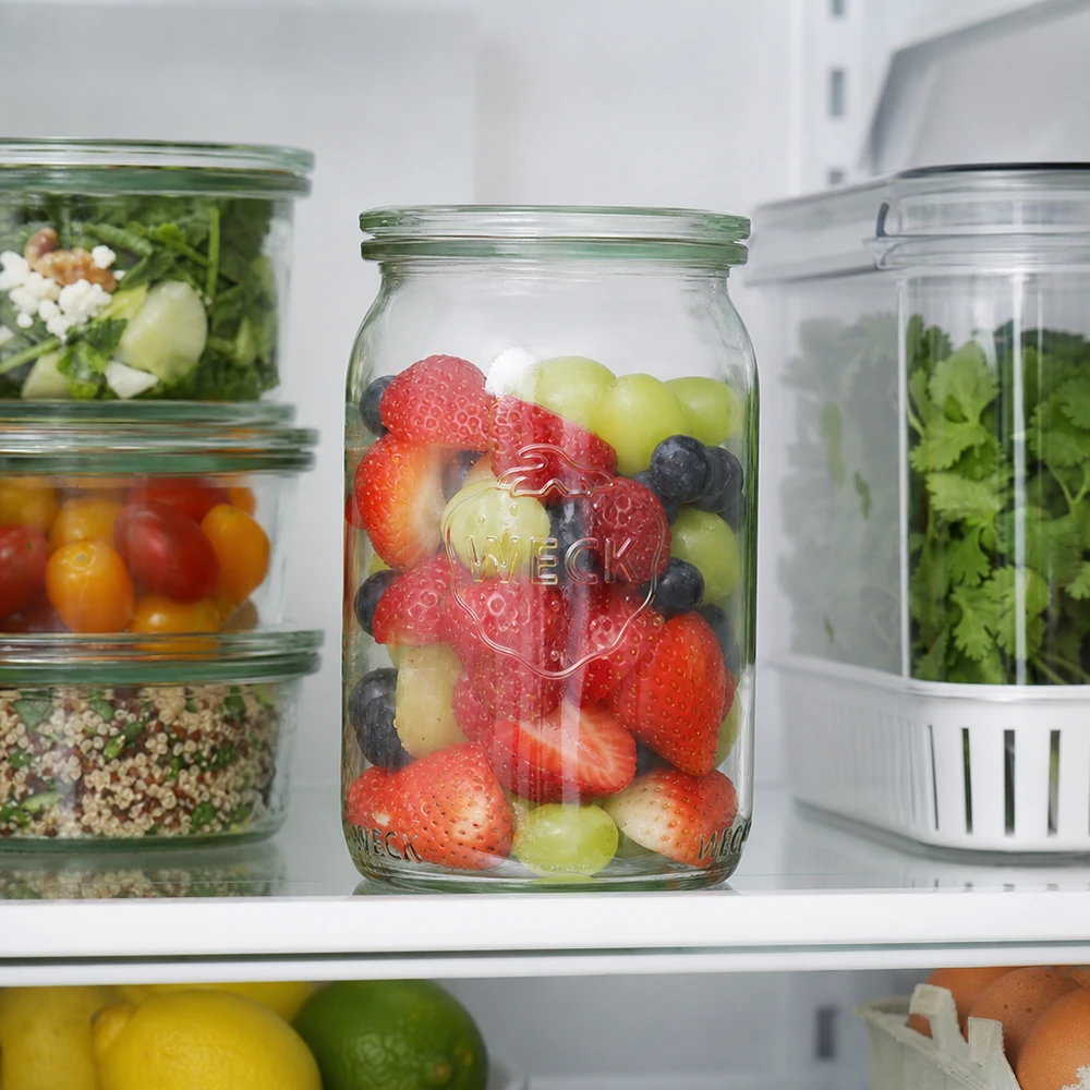 Frasco cilíndrico de 145 ml WECK RR40 com bagas frescas no frigorífico ao lado da salada e das ervas aromáticas para uma arrumação prática