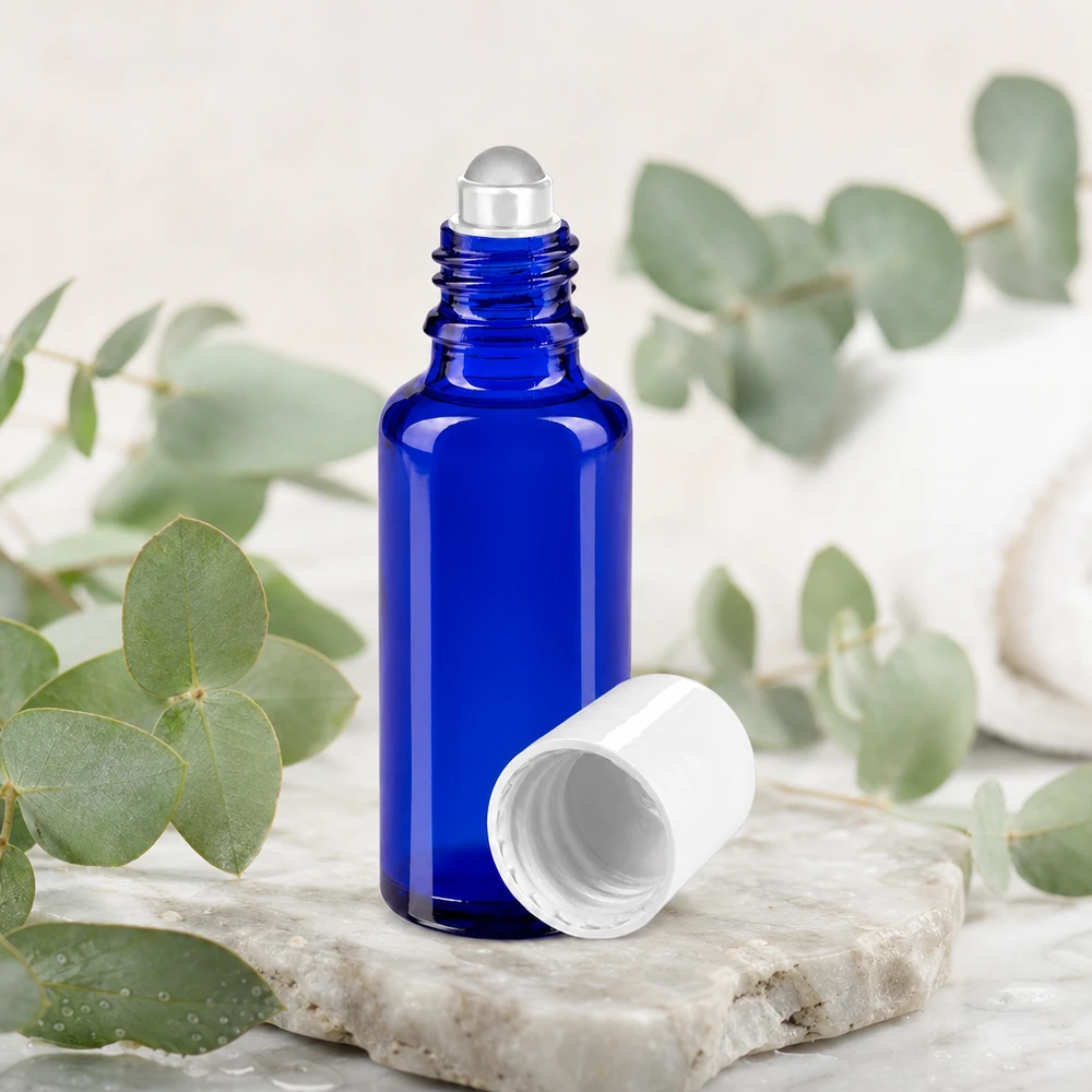 Frasco roll-on de 30 ml em vidro de farmácia azul cobalto, com tampa branca e ramos de eucalipto