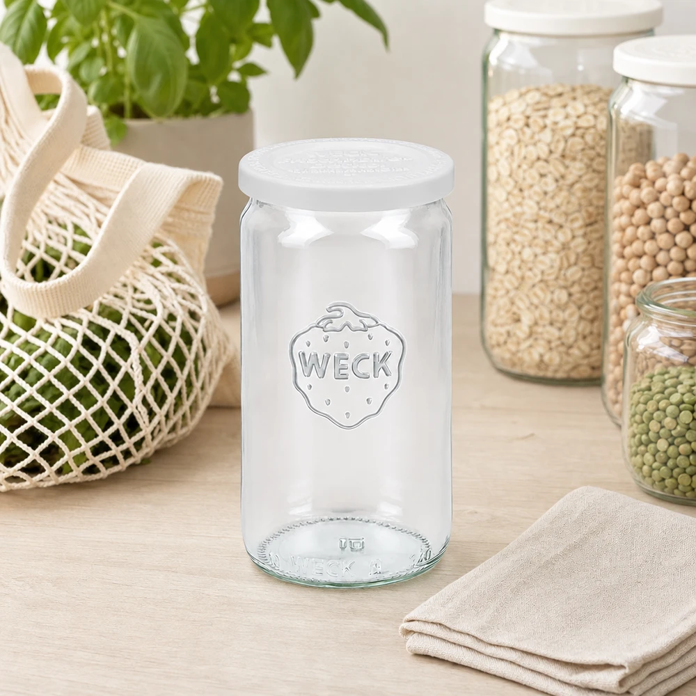 Frasco cilíndrico WECK 340ml vazio com tampa de frescura RR60 na cozinha escandinava entre frascos de arrumação e saco de rede