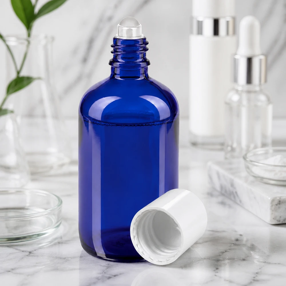Frasco de farmácia azul 100ml tampa roll-on branca Frasco de vidro azul de 100 ml com bola rolante e tampa branca sobre uma superfície de mármore