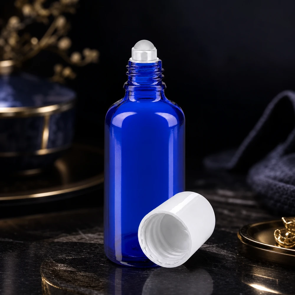 Frasco de vidro de farmácia azul de 50 ml, aberto, com tampa de bola rolante branca, sobre uma superfície de mármore escuro