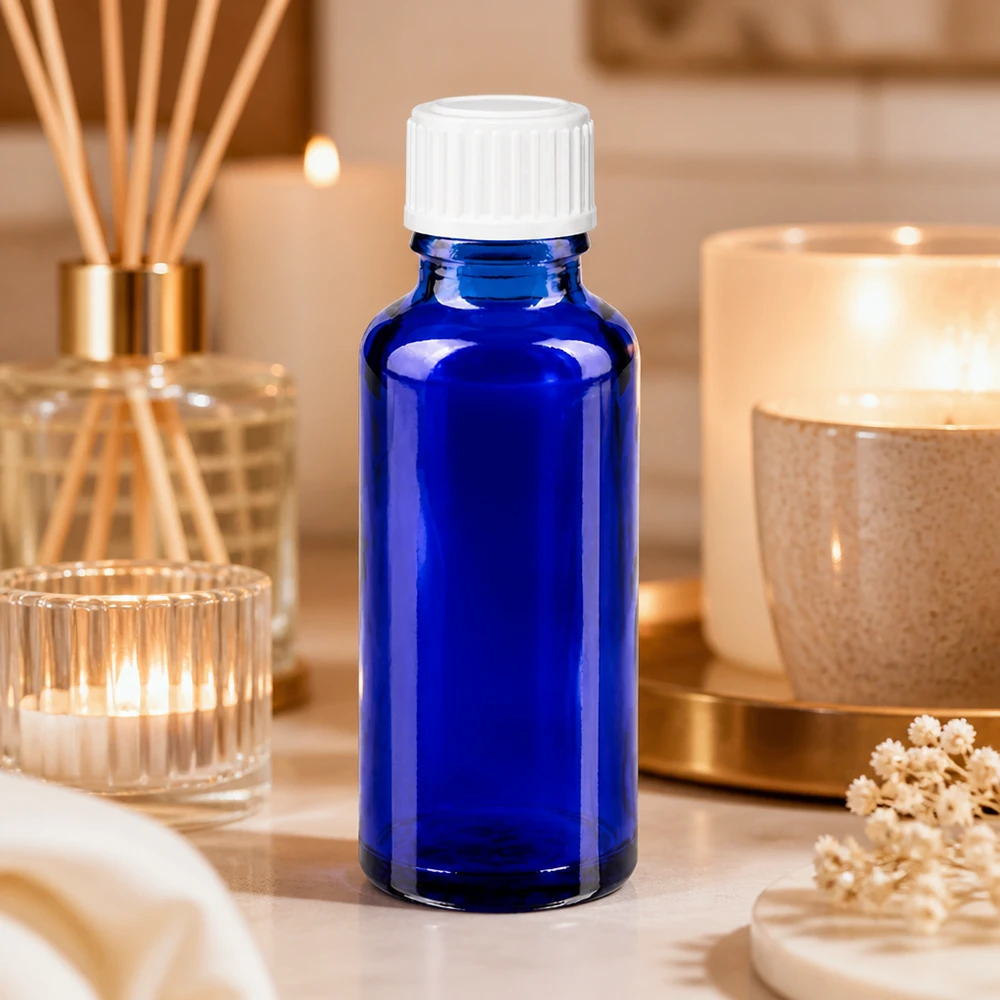 Frasco de vidro azul de 30 ml com tampa branca, rodeado por velas e varetas perfumadas