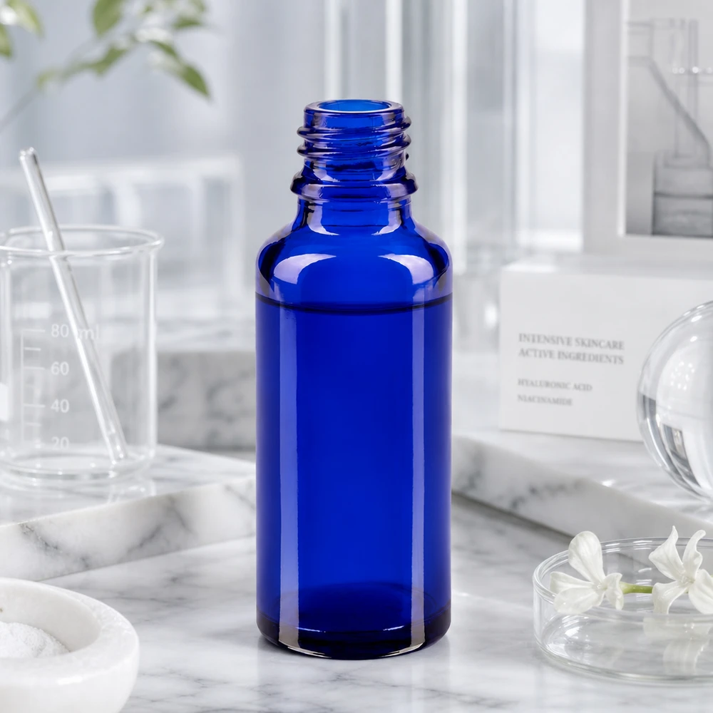Frasco ApoGlas azul cobalto de 30 ml num ambiente de laboratório, com copo medidor e ingredientes para cuidados da pele
