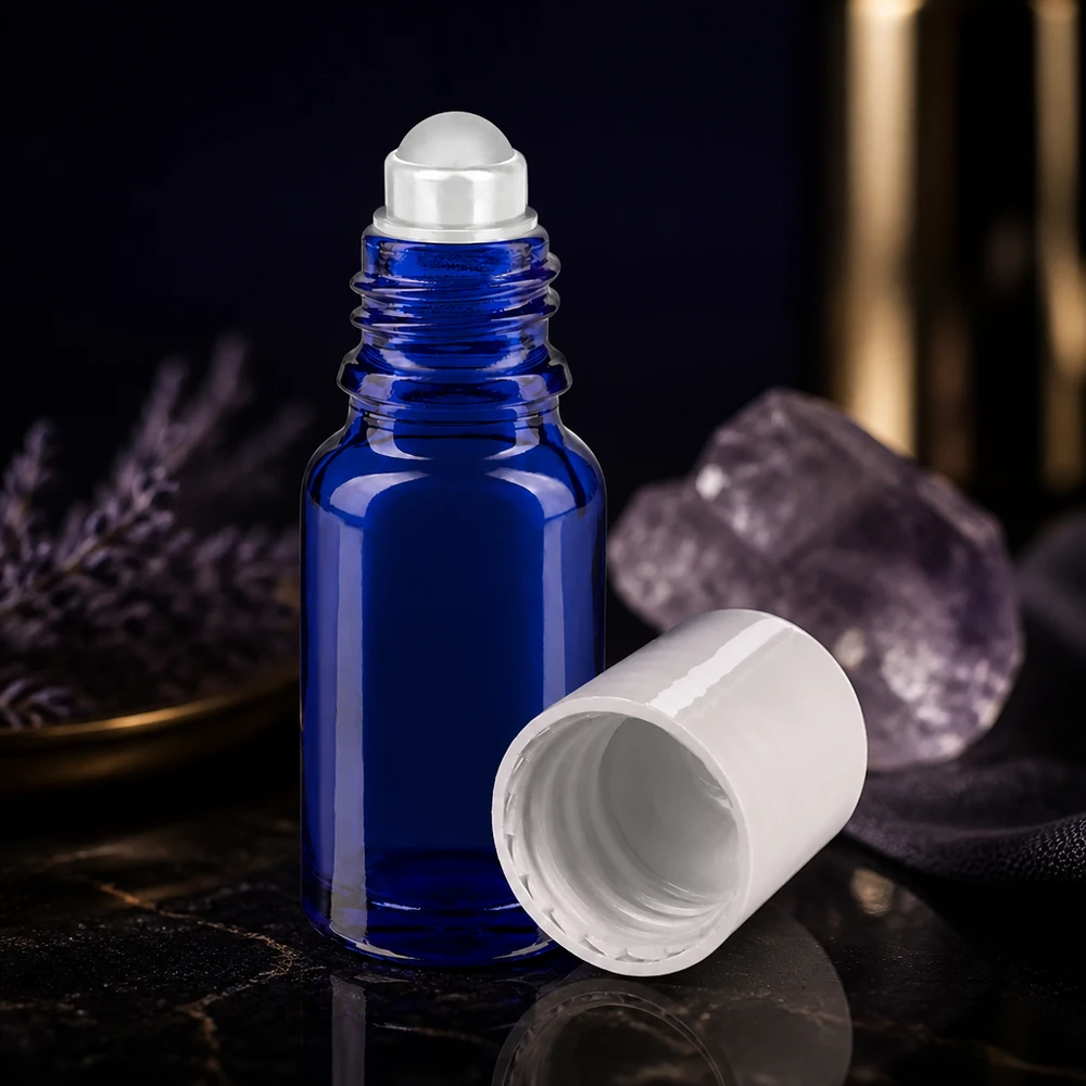 Frasco de vidro azul cobalto de 10 ml com tampa de rosca branca e esferinha transparente sobre fundo preto