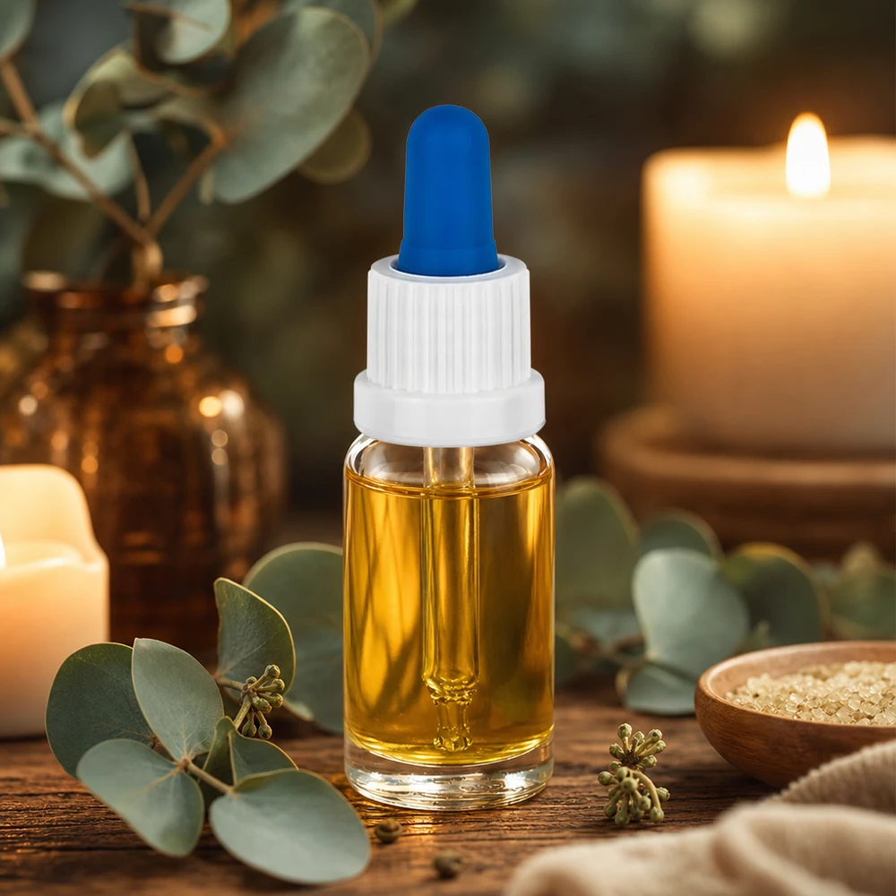 Pequeno frasco com pipeta de 10 ml, com óleo dourado, tampa branca e bola de borracha azul sobre uma mesa de madeira