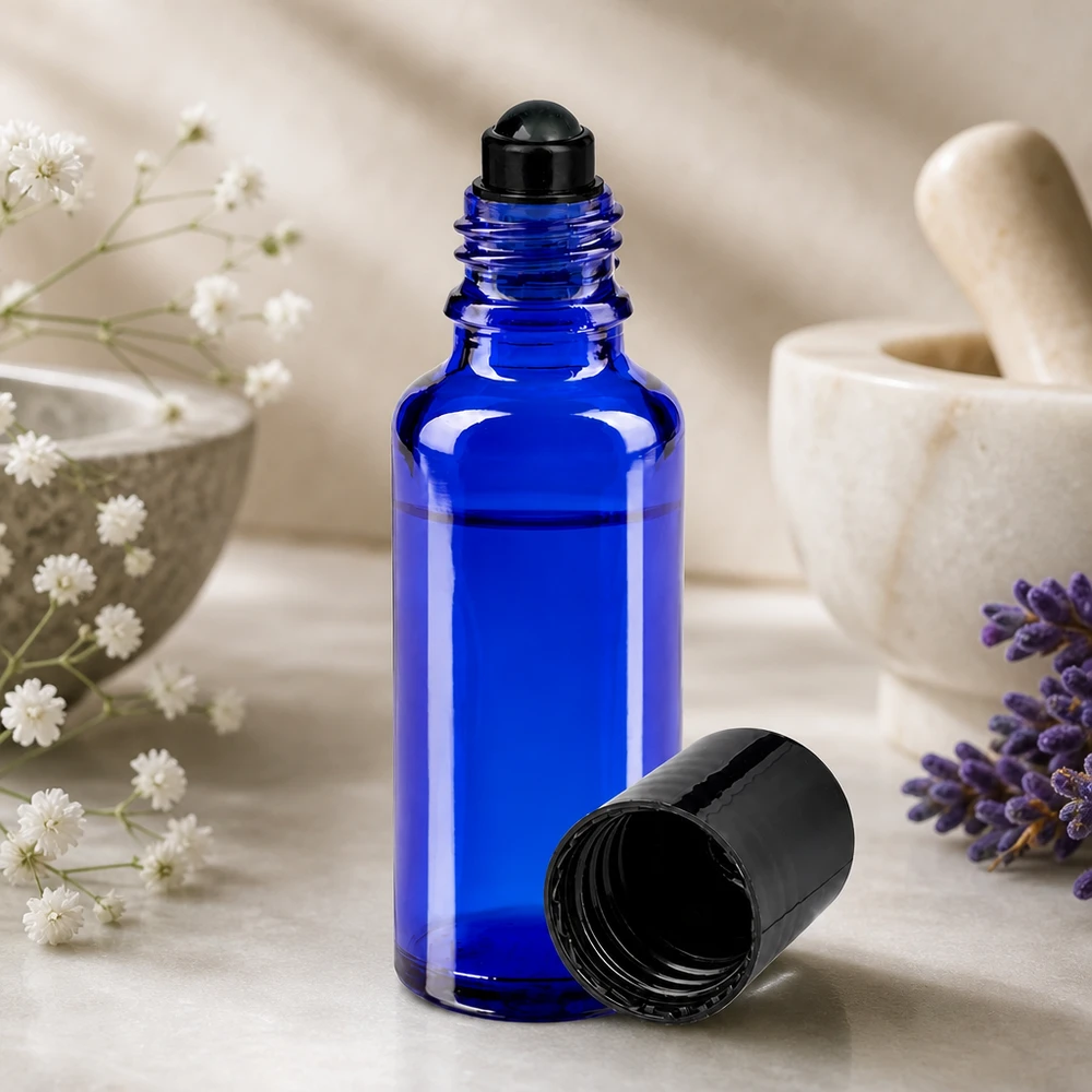 Frasco de farmácia azul 30ml com tampa de rosca preta Frasco de farmácia azul de 30 ml com bola rolante preta, ao lado de uma lavanda e de um almofariz