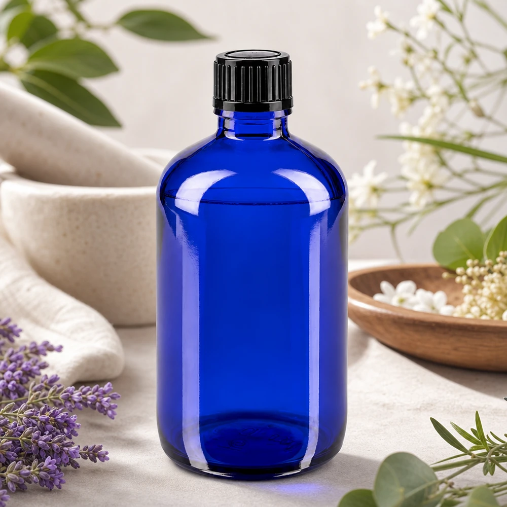 Garrafa de vidro azul de 100 ml com tampa de rosca, entre lavanda e flores brancas