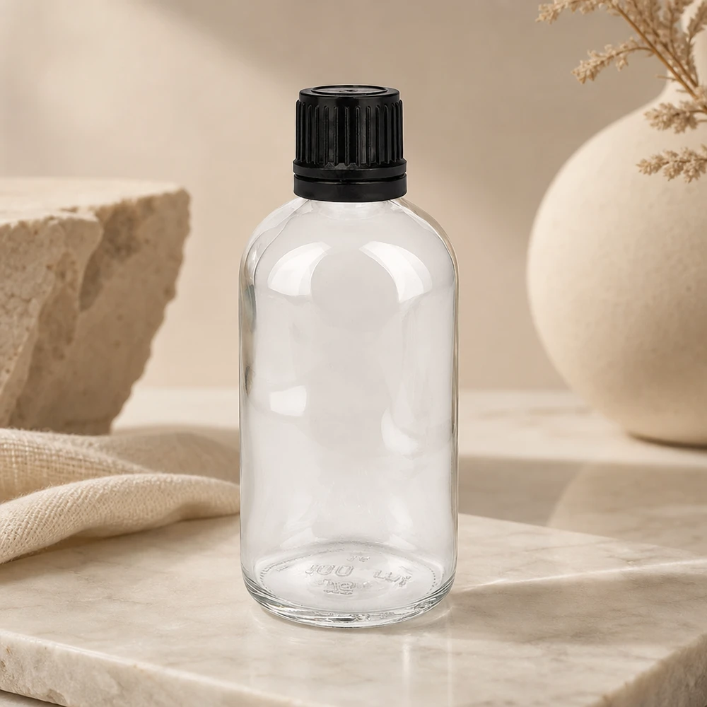 Frasco cilíndrico de vidro transparente de 100 ml com tampa preta estriada sobre fundo de mármore