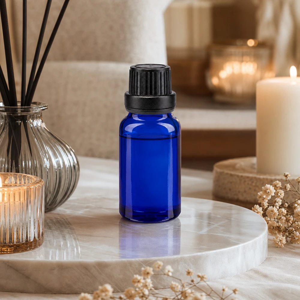 Pequeno frasco azul com conta-gotas, em vidro com proteção UV e com um inserto de 2 mm, sobre uma bandeja de mármore ao lado de velas