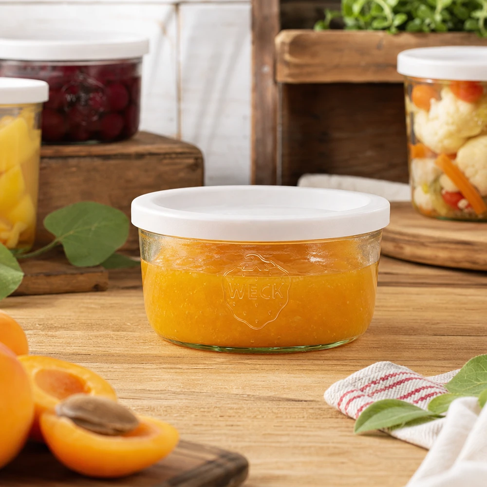 Frasco de vidro WECK de 165 ml cheio de compota de laranja num cenário de cozinha natural com frascos de conserva em segundo plano