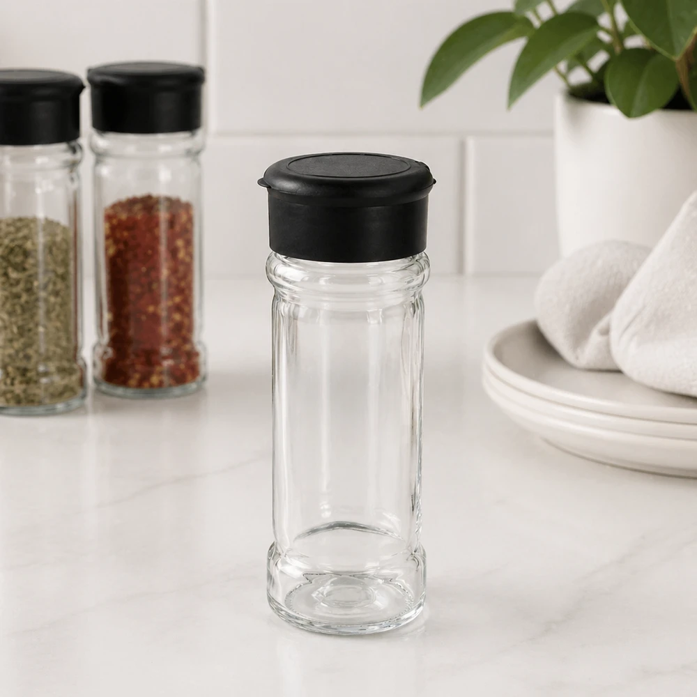 Frasco para sal/especiarias de 100 ml com espalhador, preto Pequeno frasco de sal de 100 ml com tampa preta sobre uma base de mármore branco