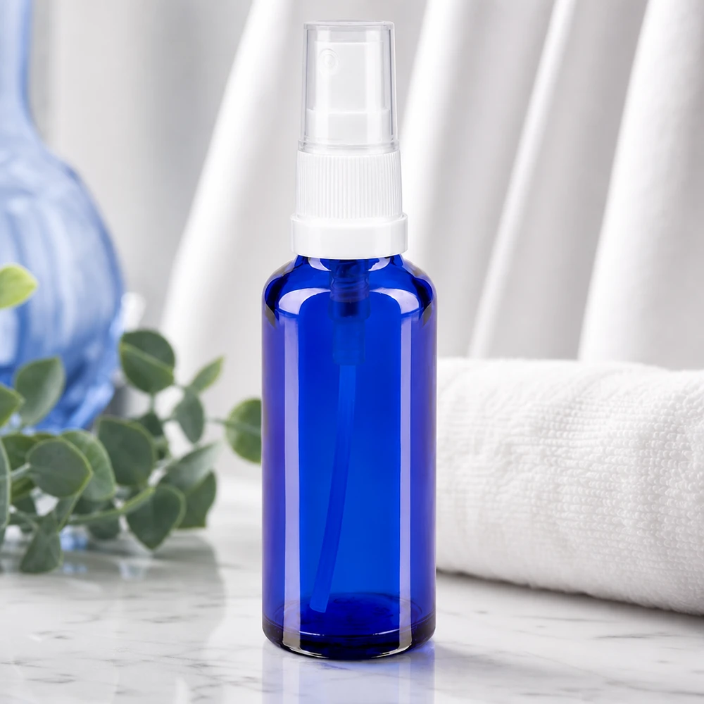 Frasco de spray azul cobalto, em vidro de farmácia, com tampa transparente, sobre mármore