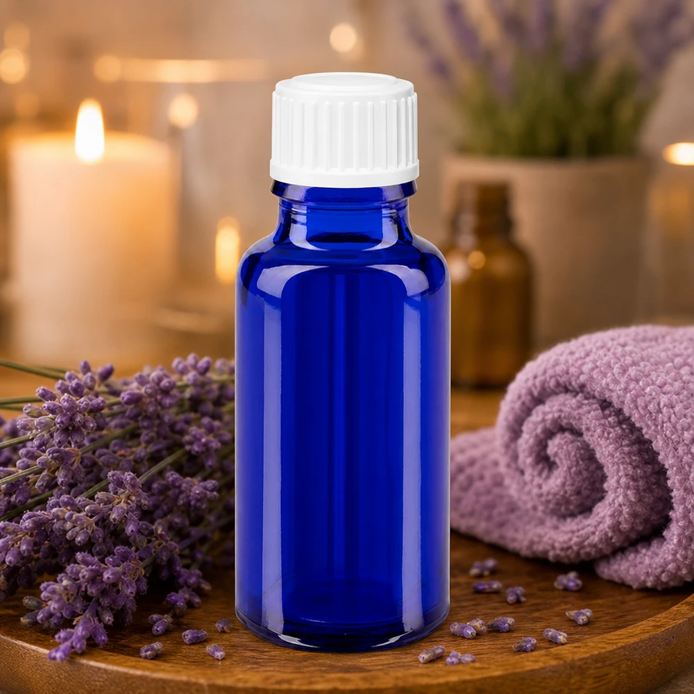 Frasco de farmácia azul 20ml tampa de rosca branco globules standard Frasco de vidro azul de 20 ml com tampa branca, rodeado por flores de lavanda numa bandeja de madeira