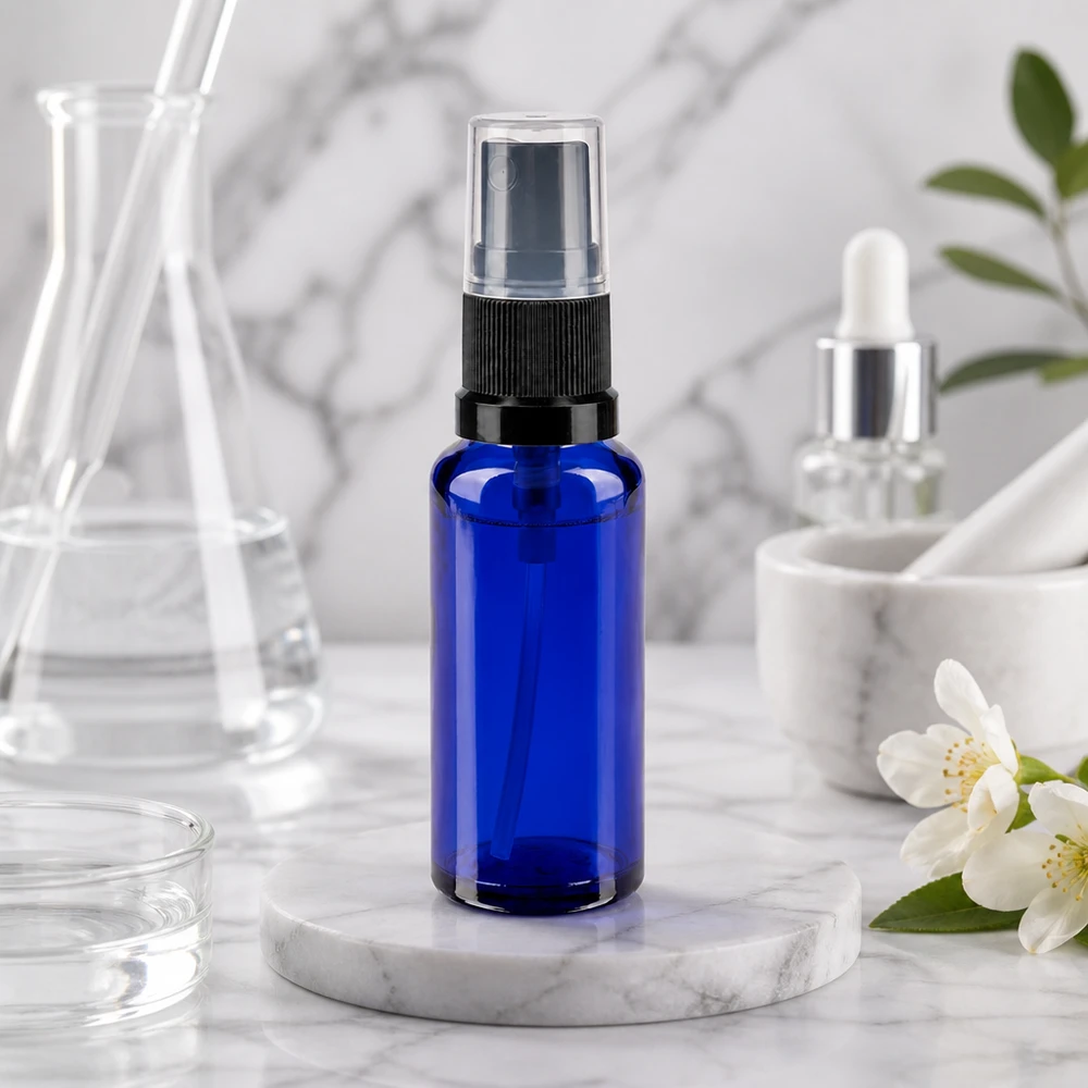 Frasco de farmácia azul 30ml spray top preto Pequeno frasco pulverizador de 30 ml em vidro de farmácia azul cobalto, com pulverizador preto sobre uma base de mármore