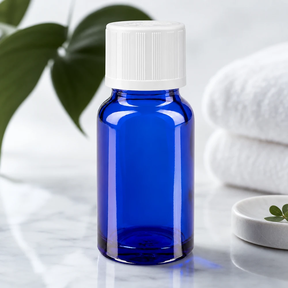 Frasco de farmácia azul de 10 ml com tampa de segurança para crianças branca, sobre mármore, ao lado de toalhas dobradas