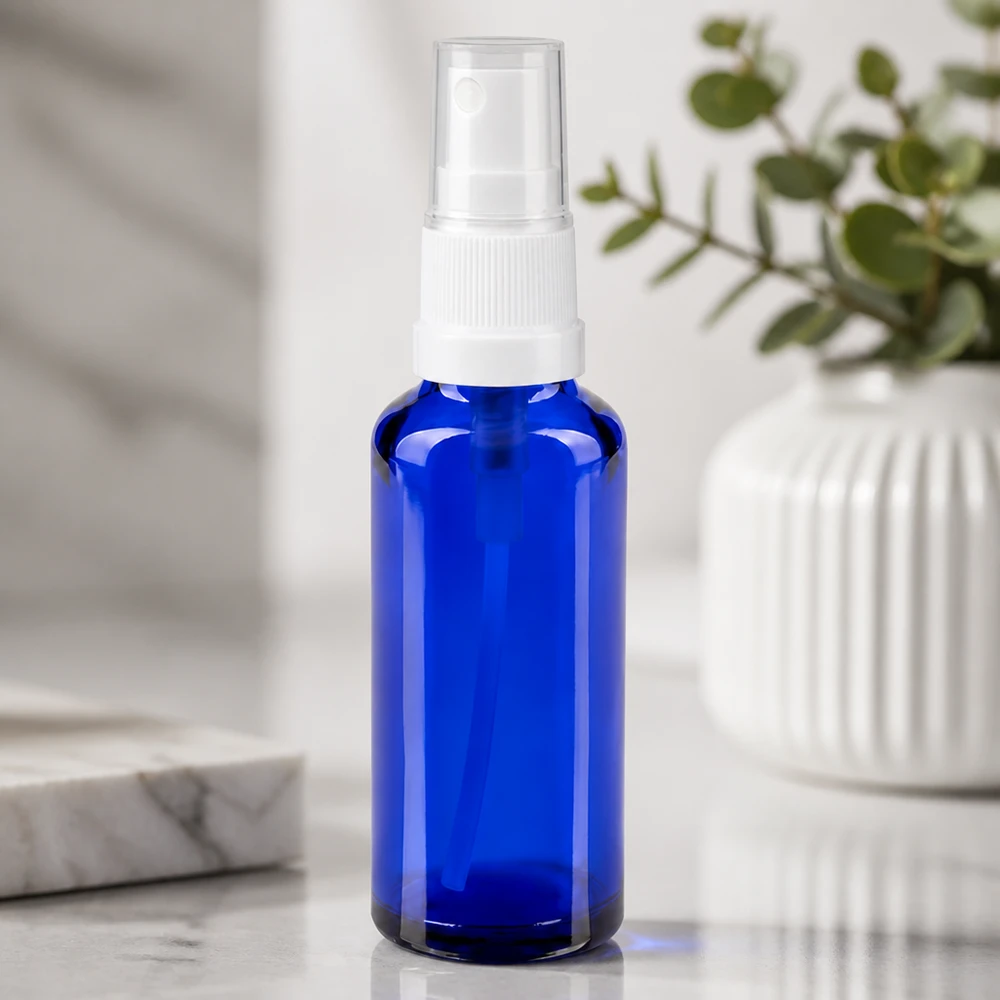 Frasco de vidro azul de farmácia de 30 ml com pulverizador branco sobre um fundo de mármore branco